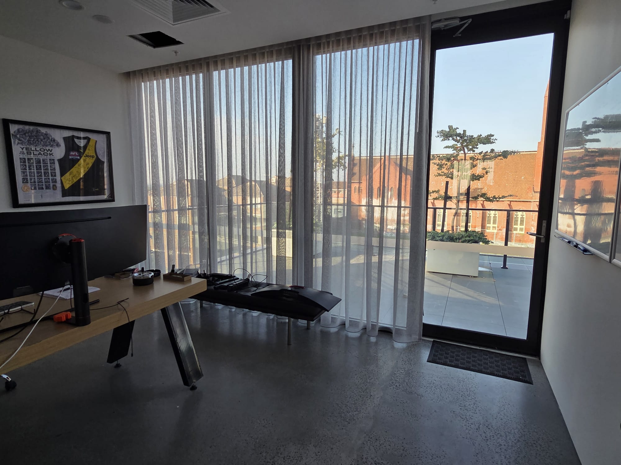 Modern office interior with a desk, computer monitor, polished concrete floor